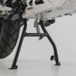 Κεντρικό σταντ SW-MOTECH σε μαύρο για BMW G 310 GS 2017–2020, τοποθετημένο σε μοτοσυκλέτα σε συνεργείο.